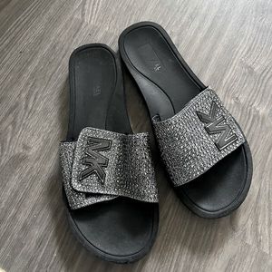 Silver and black Michael Kors slides.